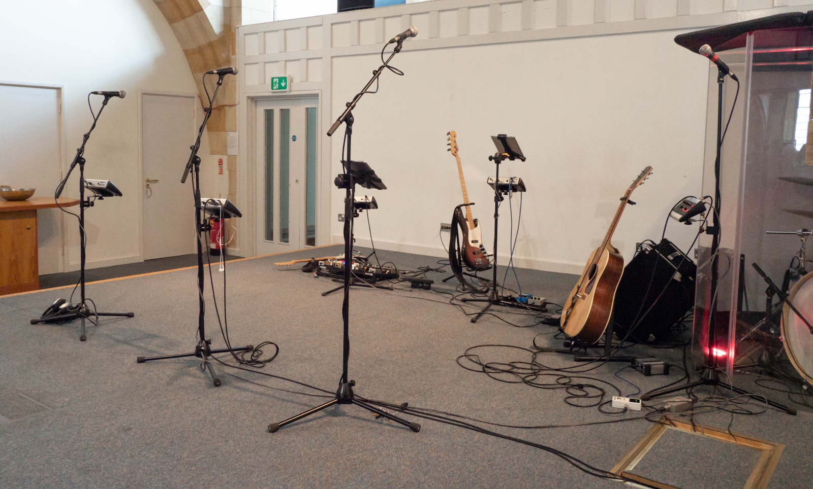 A string quartet seated in a circular formation in a wood-floored rehearsal room with a stereo microphone array on a tall stand positioned in the center, soft natural light through tall windows.