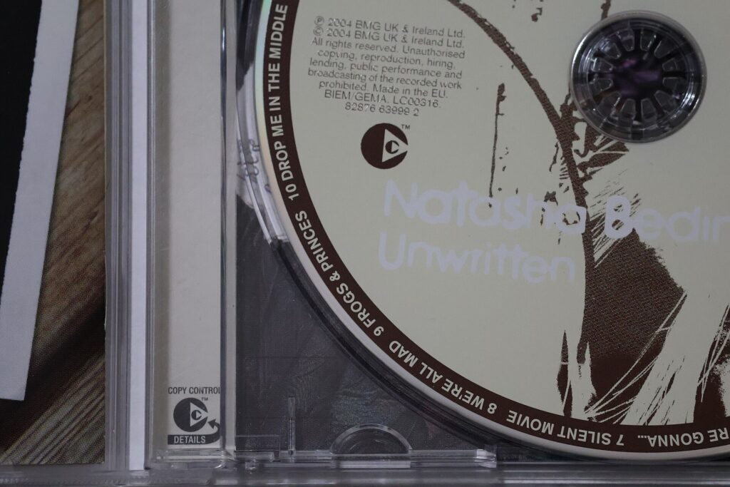Coffret de disques compacts ouvert sur une table, pochettes cartonnées empilées à côté