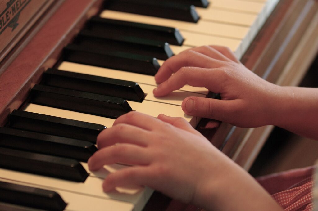 Petite salle de travail avec un piano droit, une chaise et un pupitre charg&eacute; de partitions
