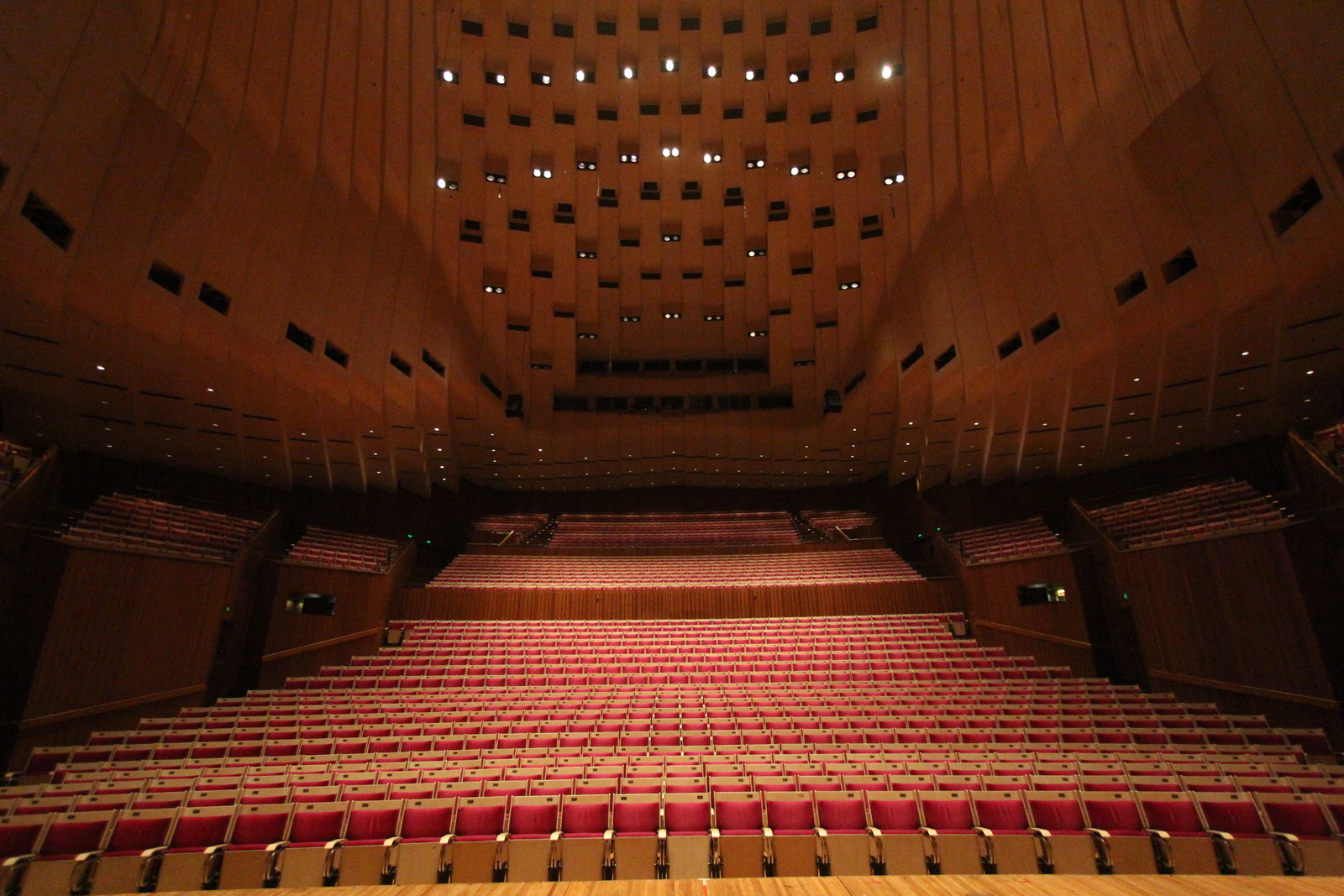 Intérieur d'une salle de concert vide, scène éclairée et fauteuils alignés au parterre
