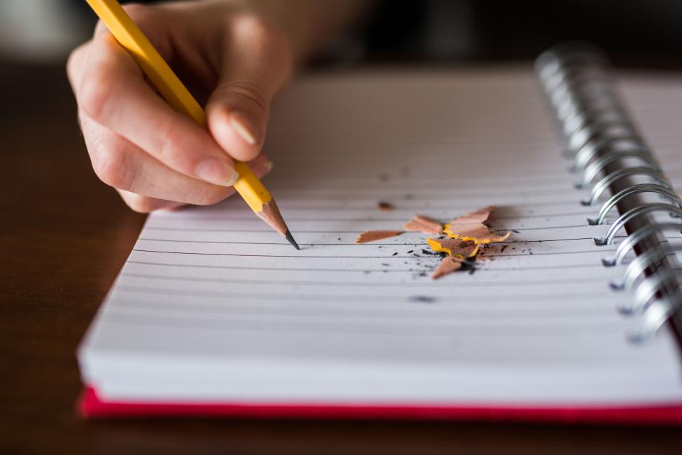 Carnet quadrillé ouvert sur une table avec un crayon posé en travers des colonnes
