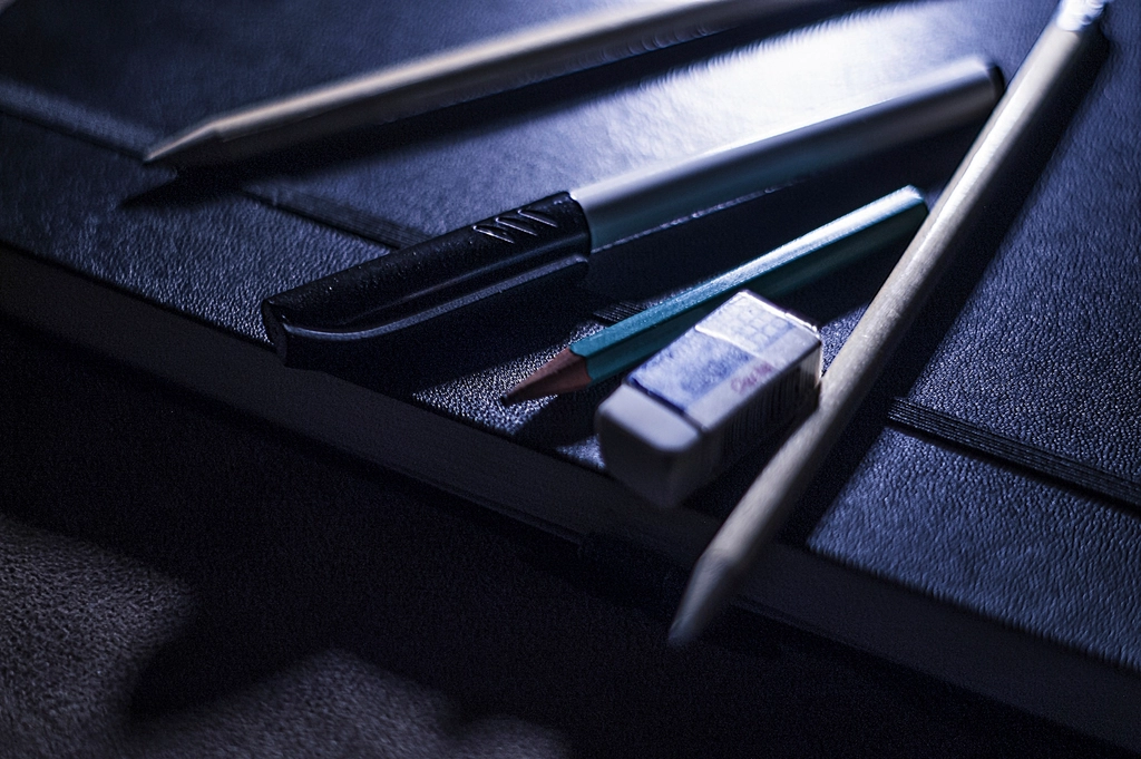 Crayon et gomme posés sur une page de musique manuscrite couverte de retouches