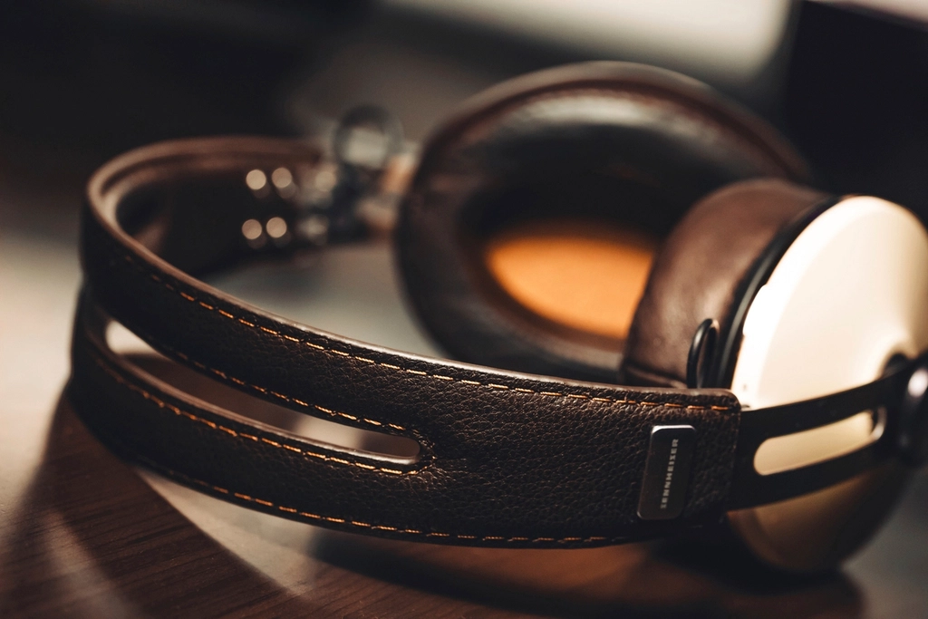 Casque audio posé sur une table en bois à côté d'un carnet ouvert et d'un crayon