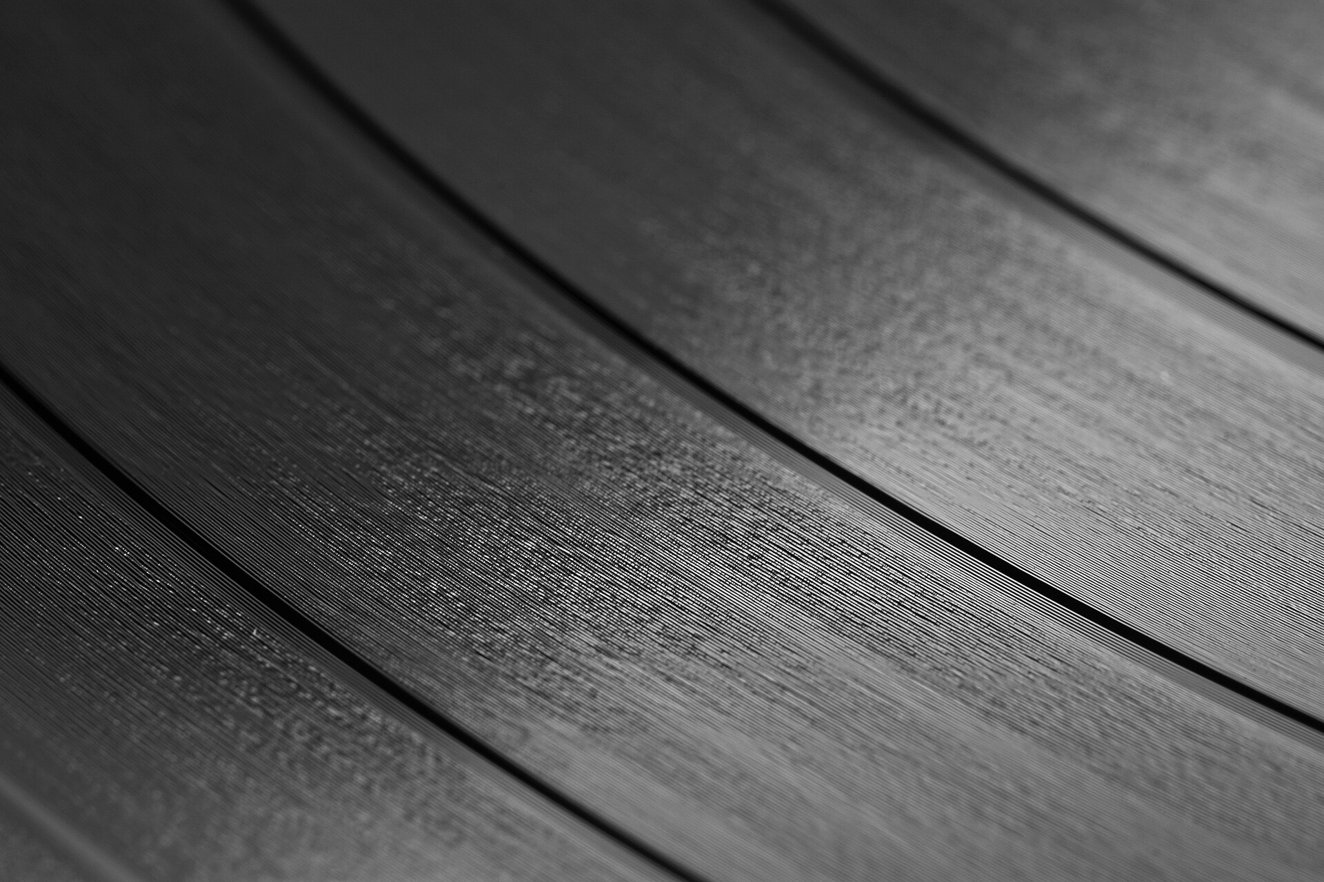 Gros plan sur les sillons d'un disque vinyle sous une lumière rasante, poussière visible en surface