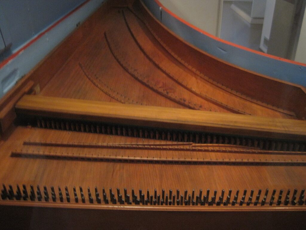 Chevilles d'accord d'un clavecin vues de près, cordes tendues et clé d'accord posée dessus