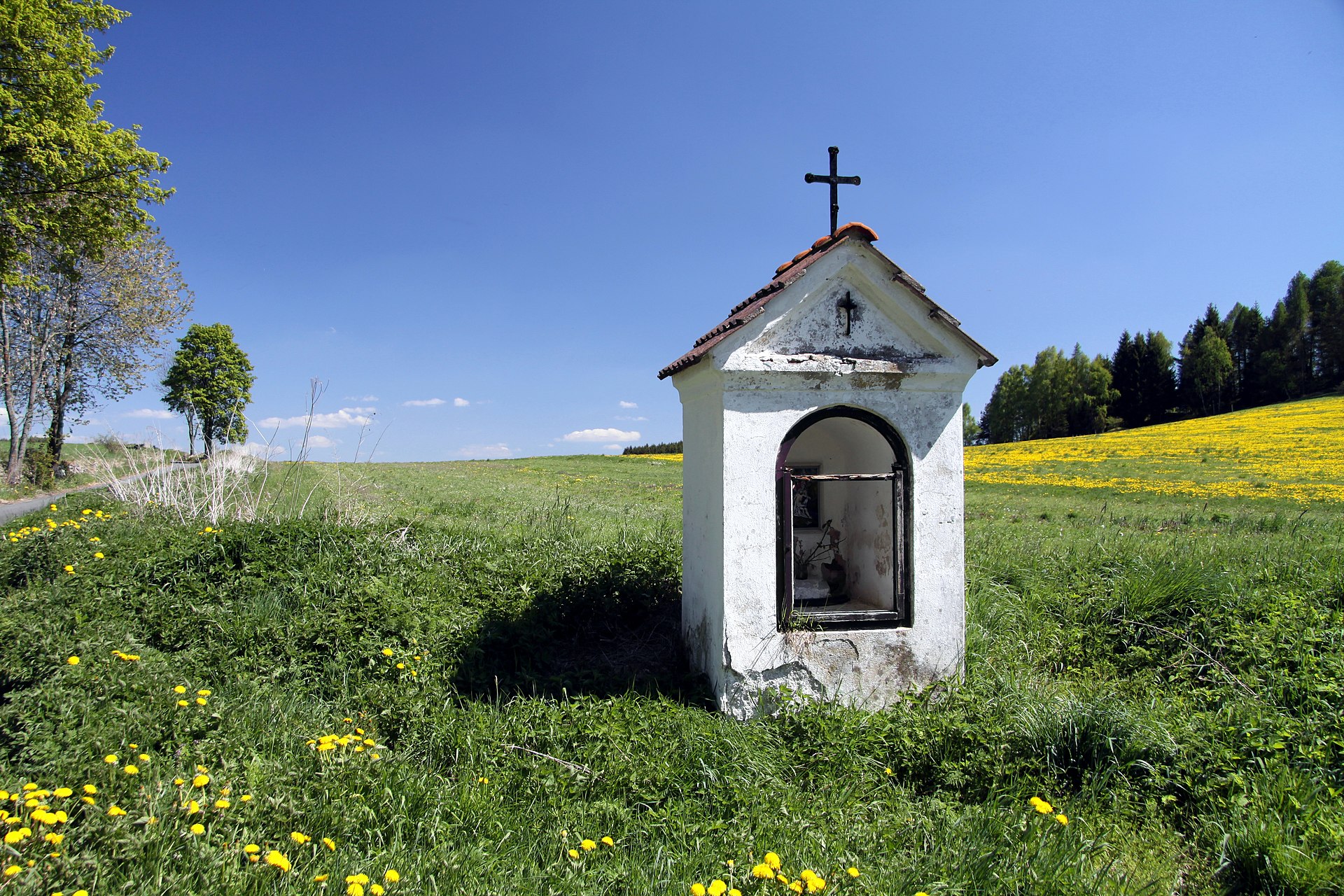 Intérieur d'une chapelle de village avec chaises alignées devant l'autel et murs de pierre nus