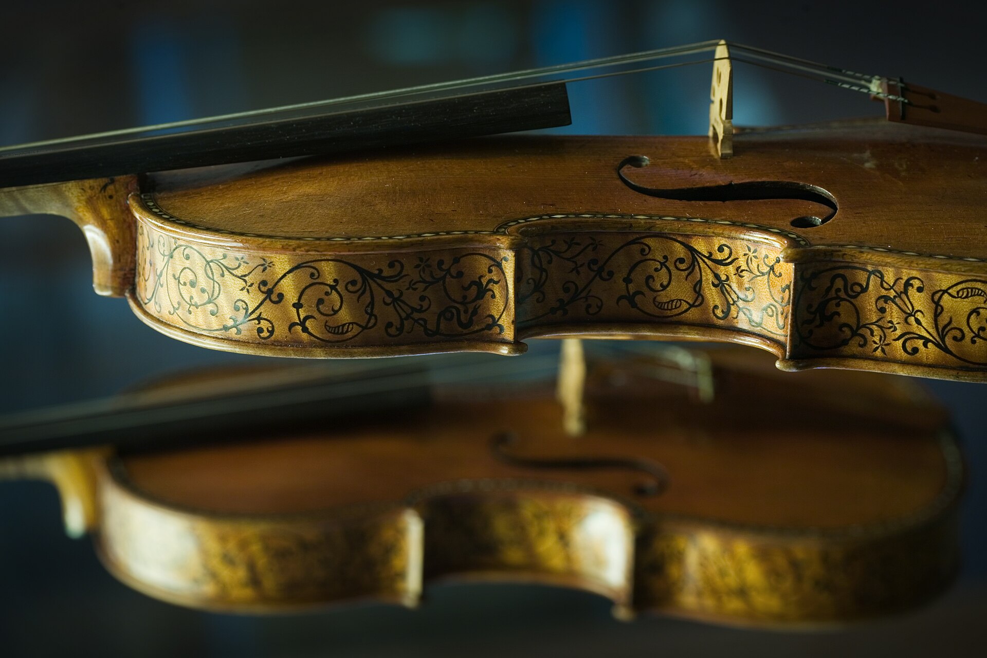 Violon ancien et archet à courbure convexe posés sur un tissu sombre, cordes en boyau visibles
