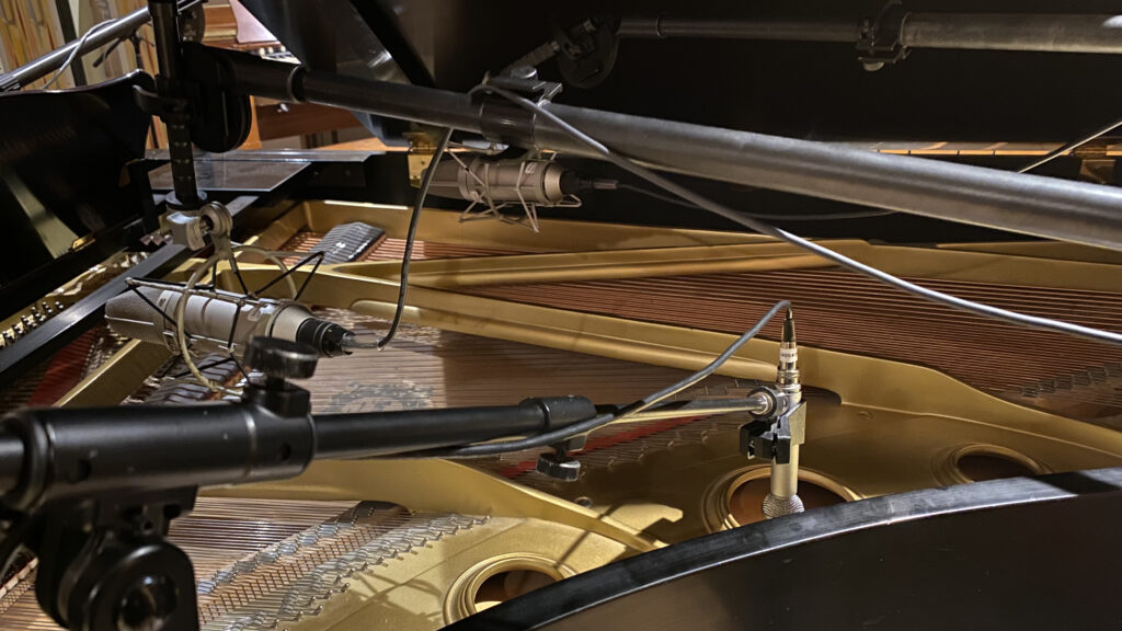 Microphone suspendu au-dessus d'un piano à queue ouvert dans une salle d'enregistrement