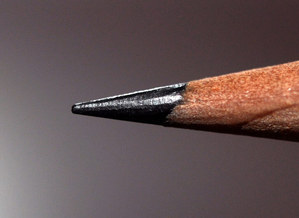 Deux crayons de papier et une gomme blanche alignés à côté d'un taille-crayon