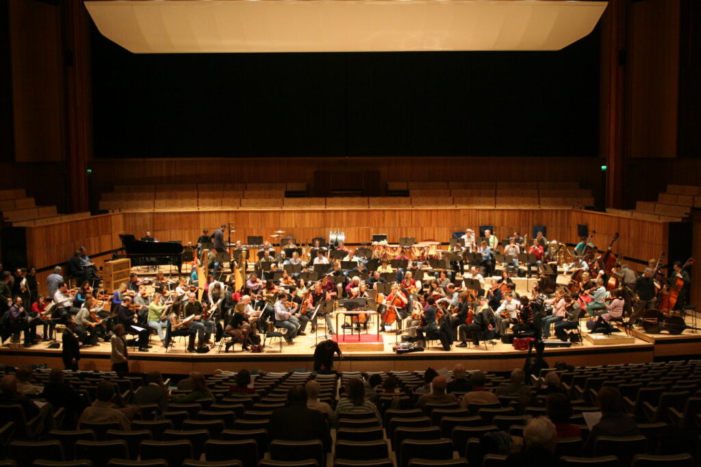 Pupitres alignés pendant une répétition d'orchestre, partitions ouvertes et instruments posés sur les chaises
